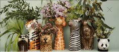 there are many vases with animals and flowers in them on the shelf next to each other