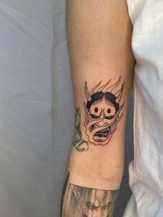 a man's arm with a tattoo on it that has an evil face and horns