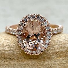 an oval shaped morganite and diamond ring on top of a rock