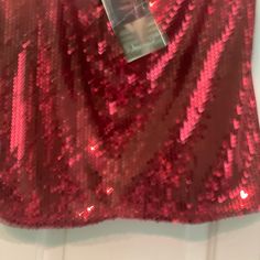 a red sequin skirt hanging on a door with a tag attached to it's side