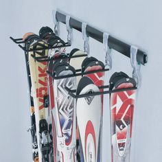 three skis are hanging on a rack in front of a white wall with two poles