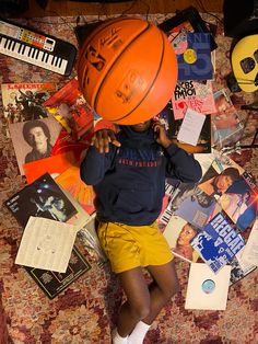 a young boy laying on top of a bed covered in lots of books and posters