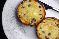 two muffins sitting on top of a white plate next to a knife and fork