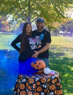 a man and woman standing in front of a table with pumpkins on it