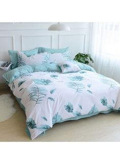 a bed with blue and white leaves on the comforter, pillows and pillowcases