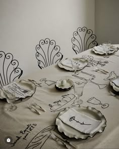 the table is set with white dishes and place settings for four people to eat at