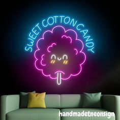 a neon sign that says sweet cotton candy on the side of a wall next to a couch