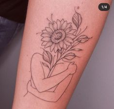 a woman's arm with a tattoo on it and a sunflower in her hand