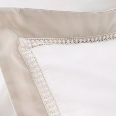 the white sheets and pillow cases have lace trimmings on them, along with an embroidered edge