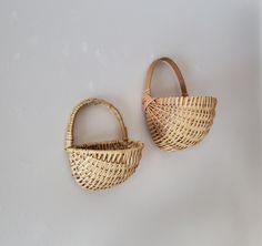 two woven baskets sitting next to each other on a white wall in front of a door