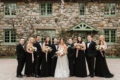 a group of people standing next to each other in front of a stone building with windows