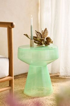 a candle sitting on top of a glass table next to a chair and window sill