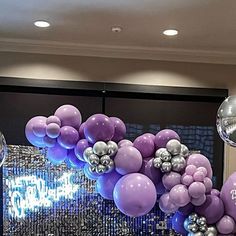 purple and silver balloons are hanging from the ceiling