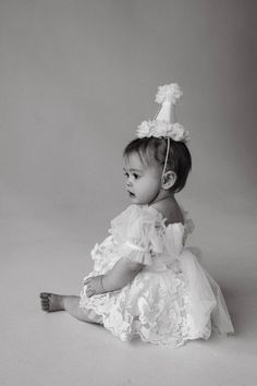 a black and white photo of a baby wearing a dress