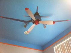 a ceiling fan mounted to the side of a blue wall in a room with white and orange trim