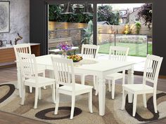 a dining room table with white chairs and a rug on the floor in front of it