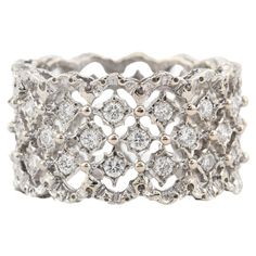 a white gold ring with diamonds on the sides and an intricate design in the middle