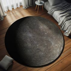 a large round black object sitting on top of a wooden floor next to a bed