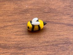 a small yellow and black toy sitting on top of a wooden table next to a mouse