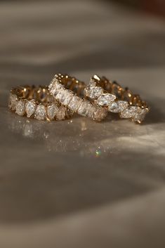 three wedding rings sitting on top of a table next to each other, with one diamond in the middle