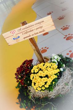 a basket filled with yellow flowers on top of a floor next to a wooden sign