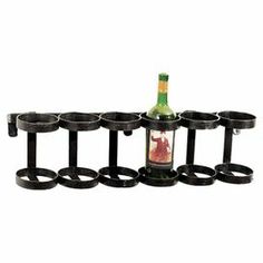 a wine bottle is sitting on a rack with eight cups in front of it and an empty