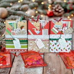 three small christmas gift bags sitting on top of a wooden table