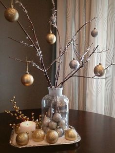 a christmas tree with ornaments in a glass vase on a tray next to a window