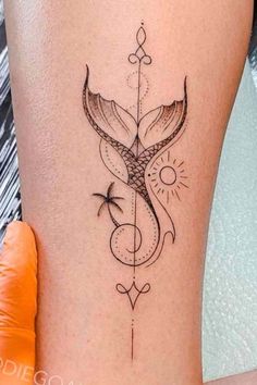 a woman's thigh with a tattoo design on her leg and an arrow in the middle