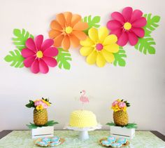 a table topped with pineapples and cakes covered in paper flowers