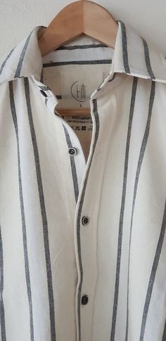 a white and black striped shirt hanging on a wooden hanger