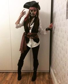 a woman dressed up as a pirate standing in front of a wall with her hands out