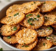 a bowl filled with crackers covered in seasoning and sprinkled with parsley