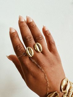 A beautiful brass double cowrie shell with a lightly textured adjustable ring band. The cowrie shell represents Goddess protection, as well as symbolizes the power of destiny and prosperity. It is perfect worn alone or with a few of our stack rings.DETAILS:Available in brass or gold plated brass Adjustable Ring Band Ships with sample polishing cloth Packaged for gift giving *Sold individually, not a set. Gold Cowrie Shell Jewelry For Gift, Gold Toe Ring Jewelry For Beach, Gold Toe Ring For Beach, Gold Shell Rings For Beach, Shell-shaped Brass Jewelry For The Beach, Adjustable Midi Rings For Beach, Handmade Gold Rings For Beach, Handmade Gold Rings For The Beach, Brass Shell Jewelry For Beach