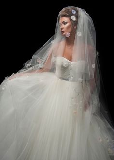 a woman in a wedding dress and veil with flowers on her head is posing for the camera