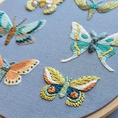 a close up of a embroidery on a piece of cloth with many different colored butterflies