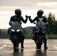 two motorcyclists in black leathers are shaking hands