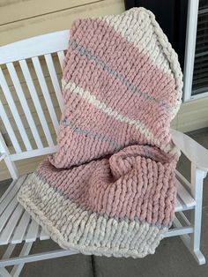 a pink and white blanket sitting on top of a wooden bench