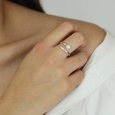 a woman wearing a pearl ring on her left hand