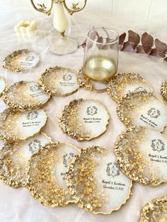 a table topped with lots of white and gold cookies next to a glass of wine