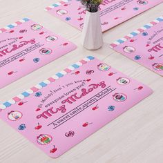 four pink placemats on a table with flowers in a vase