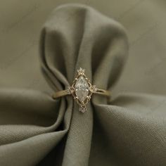 an engagement ring with a pear shaped diamond in the center on top of a green cloth