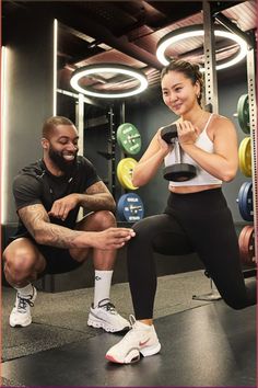 a man and woman squatting down in the gym with dumbs on their feet