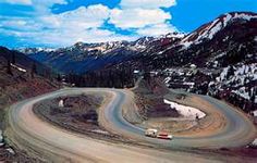 two cars driving down a winding road in the mountains