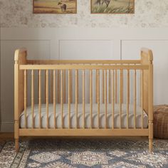 a baby crib in a room with two pictures on the wall and rugs