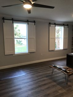 an empty living room with wood floors and two windows