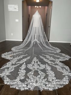 a wedding veil is laying on the floor in front of an open doorway with white walls