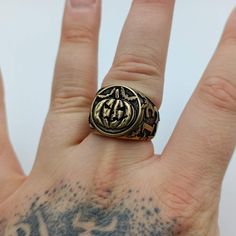 a person's hand with a gold ring on top of it and tattoos on the wrist