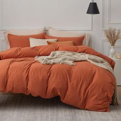 an orange comforter on a bed in a room with white walls and flooring