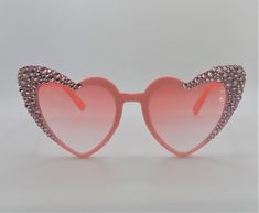 Pink heart glasses with pink crystal detail. These striking sunglasses are one-of-a-kind, with each crystal placed by hand. They make the perfect party, wedding, bridal party, festival or sunday in the sun fashion accessory. Our items are made to be exclusive and not mass-produced, meaning you are purchasing the exact pair provided in the picture so you can be sure you will love your new shades. Frame colour: Pink with pink crystal Lens colour: Pink ombre Shape: Heart Looking for something custo Glamorous Pink Tinted Sunglasses, Heart-shaped Sunglasses For Summer Weddings, Pink Heart-shaped Party Sunglasses, Elegant Heart-shaped Party Sunglasses, Heart-shaped Wedding Sunglasses For Summer, Pink Heart-shaped Sunglasses With Mirrored Lenses, Pink Heart-shaped Sunglasses As Gift, Heart-shaped Pink Sunglasses For Gift, Heart-shaped Pink Sunglasses As Gift